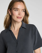 Load image into Gallery viewer, Woman wearing a short-sleeve collared button-down shirt with a relaxed fit and V-neckline
