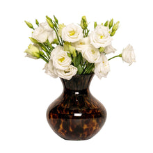 Load image into Gallery viewer, Juliska tortoiseshell glass vase filled with white lisianthus flowers on white background