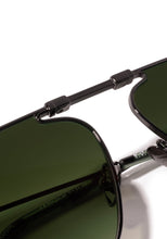 Load image into Gallery viewer, Close-up detail of Krewe Zander Fold sunglasses showing gunmetal bridge mechanism and green lenses