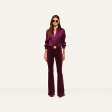 Load image into Gallery viewer, Model wearing high-rise flare velvet pants in deep wine with matching satin blouse and gold belt