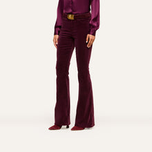 Load image into Gallery viewer, Model wearing high-rise velvet flare trousers with gold belt buckle and matching satin blouse