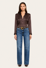 Load image into Gallery viewer, Model wearing a dark brown satin long sleeve button-up blouse tucked into straight-leg blue jeans