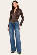 Load image into Gallery viewer, Model wearing a dark brown satin long sleeve button-up blouse tucked into wide-leg blue jeans