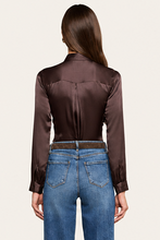 Load image into Gallery viewer, Back view of model wearing dark satin long sleeve blouse tucked into blue jeans