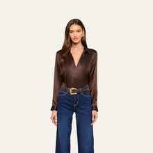 Load image into Gallery viewer, Model wearing a dark brown satin long sleeve button-down blouse tucked into wide-leg jeans
