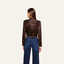 Load image into Gallery viewer, Back view of a long sleeve satin blouse tucked into dark blue wide-leg jeans